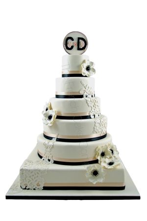 Gros plan d'un gâteau de mariage blanc orné de délicats détails colorés de type broderie, imitant des motifs floraux et des coutures complexes.