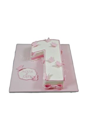 Getal 1 gevormde witte en roze verjaardagstaart gedecoreerd met sierlijke suikervlinders gemaak door The French Cake Company