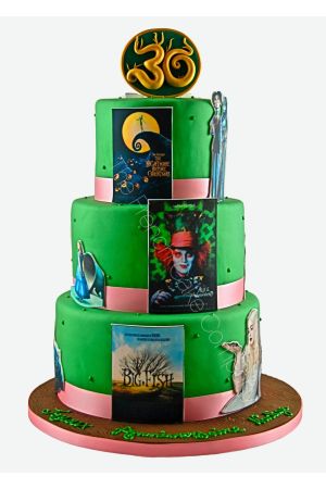 Gâteau de fête à trois étages vert décoré d'affiches comestibles et de personnages des films de Tim Burton, surmonté d'un médaillon doré.