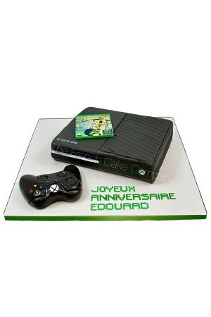 Gâteau d'anniversaire personnalisé en 3D en forme de console Xbox One noire avec sa manette en sucre et sa pochette de jeu vidéo FIFA, créé par The French Cake Company.