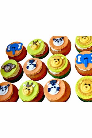 Un assortiment de cupcakes colorés décorés de visages d'animaux de la jungle en sucre 2D, comme des lions, des éléphants et des girafes.