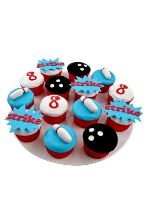 Assortiment de cupcakes d'anniversaire sur le thème du bowling avec boules noires en relief, quilles en sucre et bulles strike bleues et rouges réalisé par The French Cake Company