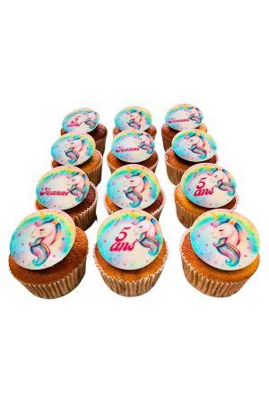 Collection of custom birthday cupcakes topped with round edible printed toppers featuring a sleeping pastel unicorn with a rainbow mane, created by The French Cake Company.
