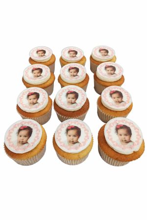 Un assortiment de cupcakes décorés de disques comestibles personnalisés affichant la photo d'une petite fille avec une bordure rose.