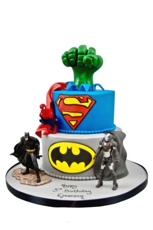 Een verjaardagstaart met twee lagen in blauw en grijs, versierd met een Hulk-vuist, Superman-logo en Batman- en Spider-Man-figuren.