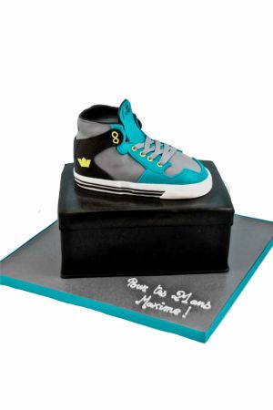 Een zeer gedetailleerde verjaardagstaart in de vorm van een blauw-witte Supra sneaker, compleet met veters, stiksels en de iconische Nike swoosh.