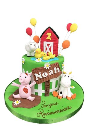Gâteau d'anniversaire vert thème ferme avec grange rouge, ballons jaunes, canetons dans la mare, cochon dans la boue et vache en sucre réalisé par The French Cake Company
