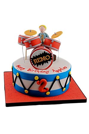 Gâteau d'anniversaire batterie de musique bleu et rouge avec figurine de batteur et cymbales en sucre conçu par The French Cake Company