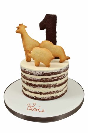 Layer cake d'anniversaire style naked cake personnalisé, surmonté de sablés artisanaux en forme d'animaux de la jungle (girafe, éléphant, lion) et du chiffre 1, créé par The French Cake Company.