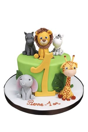 Exclusieve groene jungle verjaardagstaart gedecoreerd met het getal 1, tropische bladeren en ambachtelijke 3D suikerfiguren van een giraf, olifant, leeuw, zebra en nijlpaard, van The French Cake Company.