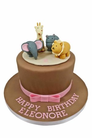 Exclusieve bruine verjaardagstaart voor meisjes in Jacadi jungle stijl met een roze strik en ambachtelijke minimalistische 3D dierfiguren van een olifant, giraf, leeuw en nijlpaard, van The French Cake Company.