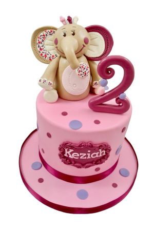 Gâteau d'anniversaire rose bonbon à pois violet et prune surmonté d'une figurine 3D de l'éléphanteau Kali de Noukie's avec imprimés fleuris réalisée par The French Cake Company
