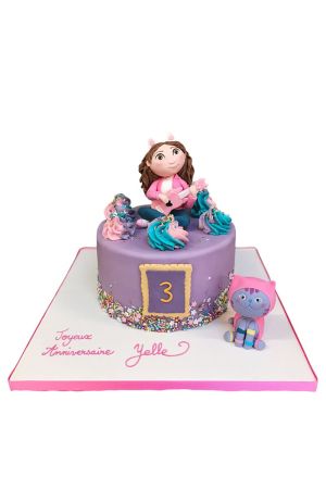 Gabby's Dollhouse birthday cake decorated with colourful sprinkles, swirl buttercream rosettes, 3D Gabby playing guitar topper, and a Pandy Paws cat figurine, created by The French Cake Company.