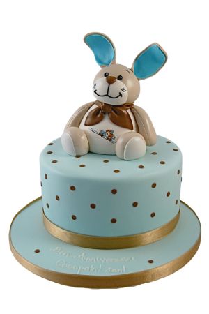 Noukies Oscar, peluche assise sur un gâteau d'anniversaire.