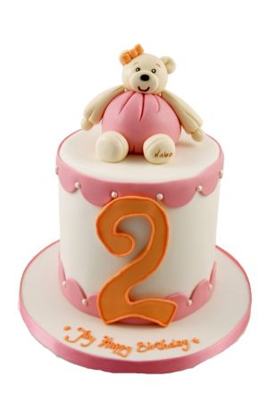 Gâteau d'anniversaire personnalisé blanc et rose orné d'une bordure festonnée, de perles nacrées, d'un grand chiffre 2 orange et d'un ourson en peluche Kaloo rose sculpté en 3D, créé par The French Cake Company.
