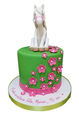 Little horse sitting on a pretty cake with flowers