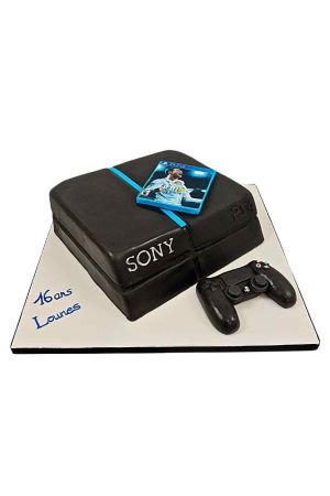 Un gâteau d'anniversaire sculpté en 3D en forme de console PS4 noire avec une manette de jeu réaliste et une image comestible du jeu FIFA.