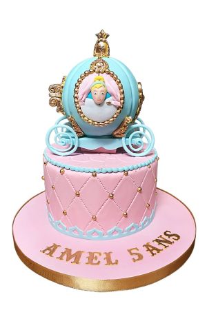 Sprookjesachtige roze gewatteerde verjaardagstaart met een 3D lichtblauwe Assepoester koets, gouden wielen en gouden pareltjes gemaakt door The French Cake Company