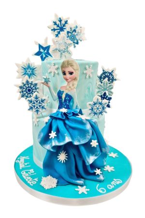 Gâteau d'anniversaire à deux étages bleu La Reine des Neiges orné de la robe drapée en pâte à sucre d'Elsa, d'une pluie de flocons scintillants et d'étoiles, créé par The French Cake Company.
