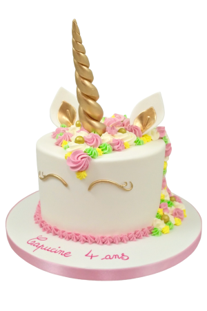 Custom round white unicorn birthday cake featuring a tall golden twisted horn, matching golden ears and eyelashes, and a pastel piped buttercream mane with gold pearls, handcrafted by The French Cake Company.