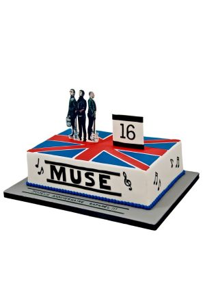 Een rechthoekige witte fondant verjaardagstaart met de rood-wit-blauwe Union Jack vlag op de bovenkant, staande figuren van de band Muse, een bordje met het getal 16 en zwarte muzieknoten op de zijkant.