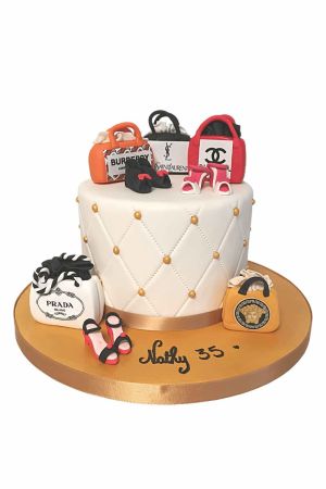 Een witte gecapitonneerde fondant taart versierd met eetbare miniatuur handtassen en schoenen van luxe modemerken.
