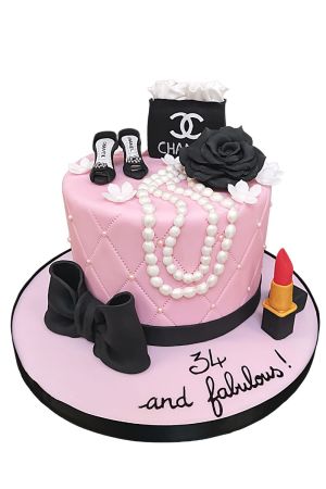 Gâteau d'anniversaire glamour rose matelassé avec colliers de perles en sucre, talons hauts, sac Chanel, rose noire et rouge à lèvres conçu par The French Cake Company
