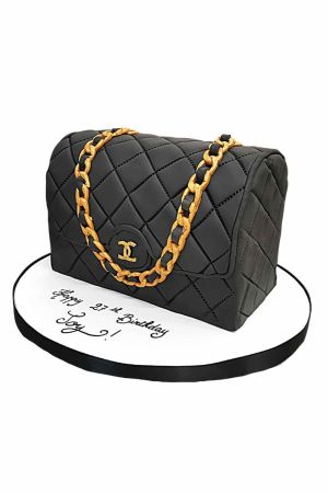 Gâteau d'anniversaire sculpté en forme de sac à main Chanel noir matelassé avec chaîne dorée et fermoir entrelacé par The French Cake Company