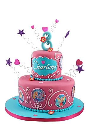 Two-tier pink and turquoise Barbie birthday cake decorated with edible doll medallions, white scrollwork, pink sugar flowers, and curly wire topper with sparkling hearts and stars, created by The French Cake Company.