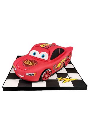 Gâteau d'anniversaire sculpté en 3D en forme de voiture Flash McQueen rouge avec logos officiels et numéro 95 sur plateau à damier noir et blanc par The French Cake Company