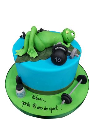 Fun blue birthday cake featuring a relaxing green frog, barbells, dumbbells, and kettlebell by The French Cake Company