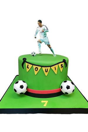 A detailed close-up of a birthday cake decorated in a football theme, featuring an edible image of Cristiano Ronaldo.