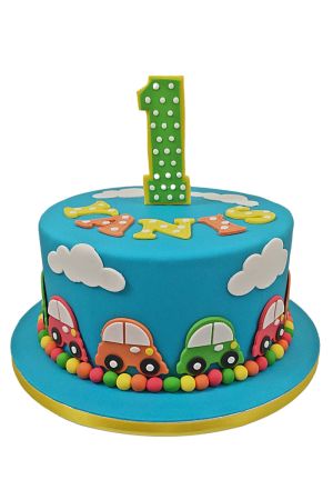 Gâteau du 1er anniversaire bleu turquoise décoré de petites voitures colorées, de nuages blancs, d'une bordure de perles en sucre et du chiffre 1 vert à pois réalisé par The French Cake Company