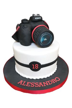 Gâteau d'anniversaire personnalisé de luxe à fond blanc, surmonté d'un appareil photo reflex Canon en 3D sculpté en sucre, créé par The French Cake Company.