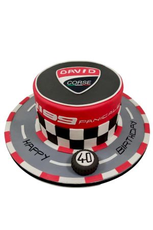 Gâteau d'anniversaire sur mesure Ducati Corse rouge et noir avec motifs drapeau à damier et socle en forme de circuit automobile, créé par The French Cake Company.