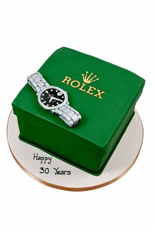 Un gâteau d'anniversaire de luxe en forme de boîte de montre Rolex verte avec une montre en sucre argentée et le logo Rolex doré.
