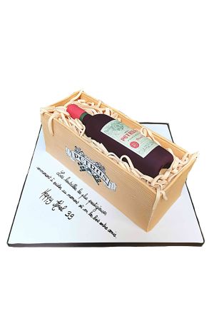 Gâteau d'anniversaire trompe-l'œil 3D représentant une bouteille de vin Petrus couchée dans une caisse en bois garnie de paille en sucre, créé par The French Cake Company.