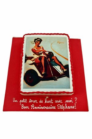 Gâteau d'anniversaire rectangulaire imprimé style pin-up rétro sur un karting, bordé d'une tresse de glaçage rouge, créé par The French Cake Company.