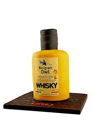 Exclusieve 3D verjaardagstaart gemodelleerd als een staande fles Belgian Owl Single Malt whisky op een donkere hout-effect onderplaat, van The French Cake Company.