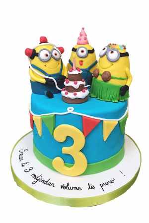 Exclusieve blauwe Minions film verjaardagstaart met gekleurde vlaggetjes, nummer 3 en drie 3D Minion figuurtjes rond een mini taartje, van The French Cake Company.