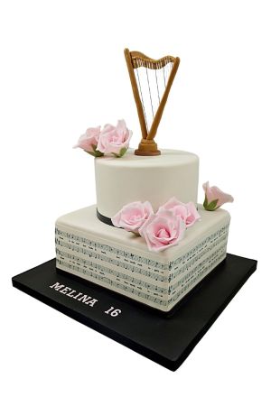 Gâteau d'anniversaire raffiné à deux étages avec harpe dorée, roses en sucre roses et portée de musique créée par The French Cake Company