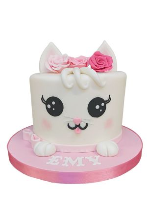 Gâteau d'anniversaire chaton blanc mignon avec oreilles sculptées, couronne de roses en sucre roses, grands yeux expressifs et petites pattes en relief par The French Cake Company