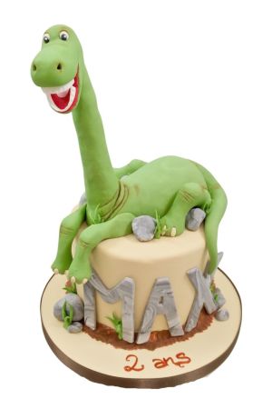 Un dinosaure géant assis sur un gâteau d'anniversaire avec le nom et l'âge inscrits en lettres imitant la pierre.