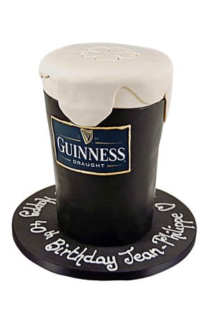 Un gâteau d'anniversaire en forme de pinte de Guinness, avec une base brun foncé, une mousse blanche crémeuse et une texture mousseuse.