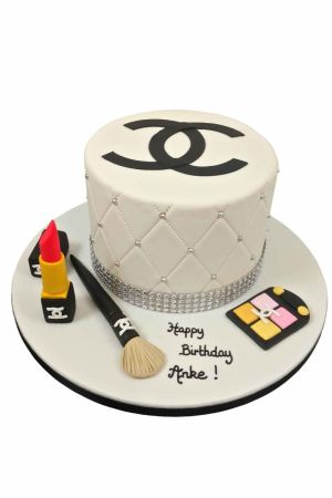 Gâteau d'anniversaire blanc matelassé orné du logo Chanel noir, rangée de strass, pinceau à maquillage, ombre à paupières et rouge à lèvres en sucre par The French Cake Company