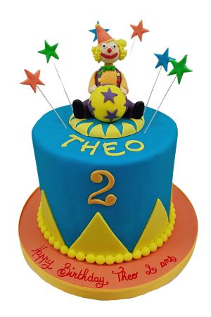 Vibrant blue circus clown birthday cake featuring a sculpted clown sitting on a ball with star toppers on wires