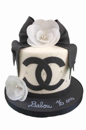 Gâteau d'anniversaire style Chanel avec fondant matelassé ivoire, logo CC noir, grand nœud et fleurs de camélia blanches en sucre par The French Cake Company