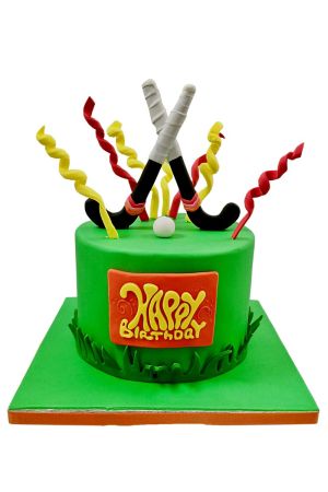 Gâteau d'anniversaire rond vert thème hockey sur gazon avec crosses croisées en sucre et serpentins colorés par The French Cake Company