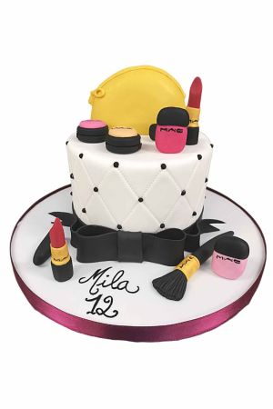 Un gâteau d'anniversaire blanc au motif matelassé décoré de cosmétiques en sucre comestibles, dont du rouge à lèvres et un pinceau.