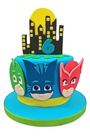 Un gâteau d'anniversaire bleu vif orné des visages de Yoyo, Bibou et Gluglu, surmonté d'une silhouette de ville noire et d'une lune jaune.